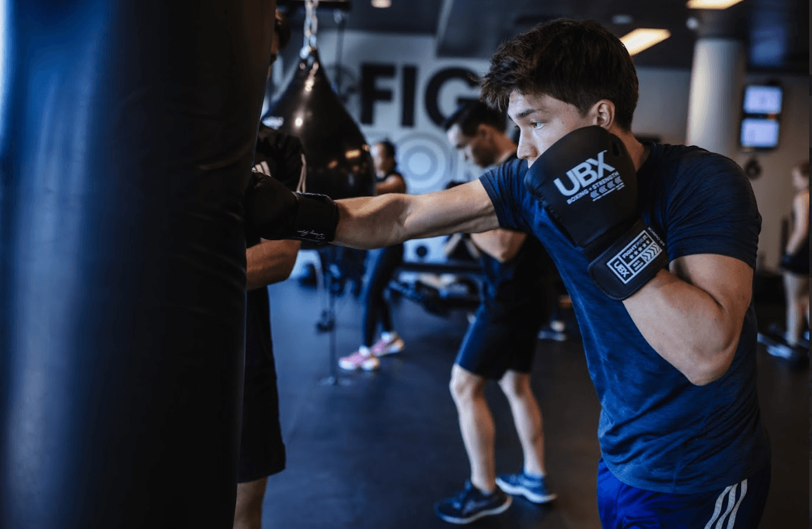 Male athlete throwing a powerful punch at a heavy bag during a UBX Training Ealing workout.