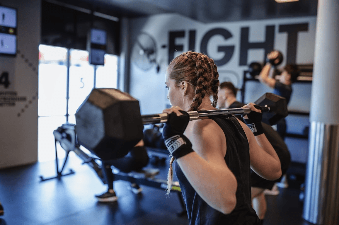 Female member focused on lifting weights during a strength session at UBX Training Ealing.