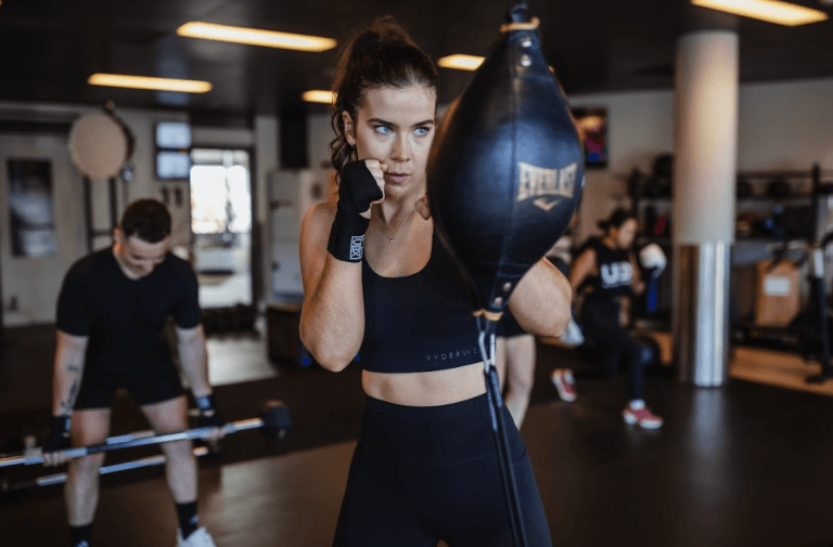 Female athlete delivering a punch to the boxing bag during a workout at UBX Training Ealing.