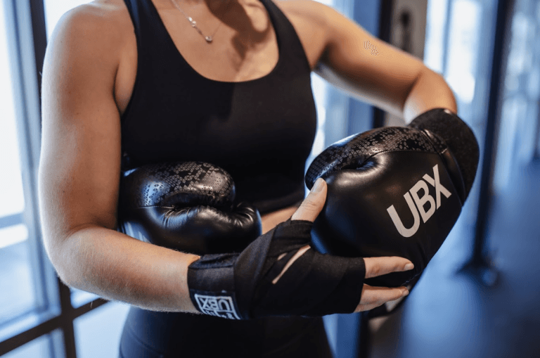 Female boxer wearing gloves, ready for training at UBX Training Ealing.