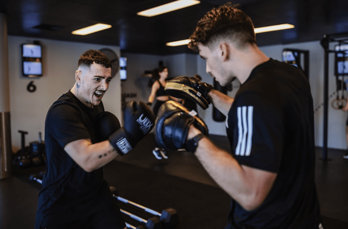 Two male boxers practicing techniques together during a training session at UBX Training Ealing.
