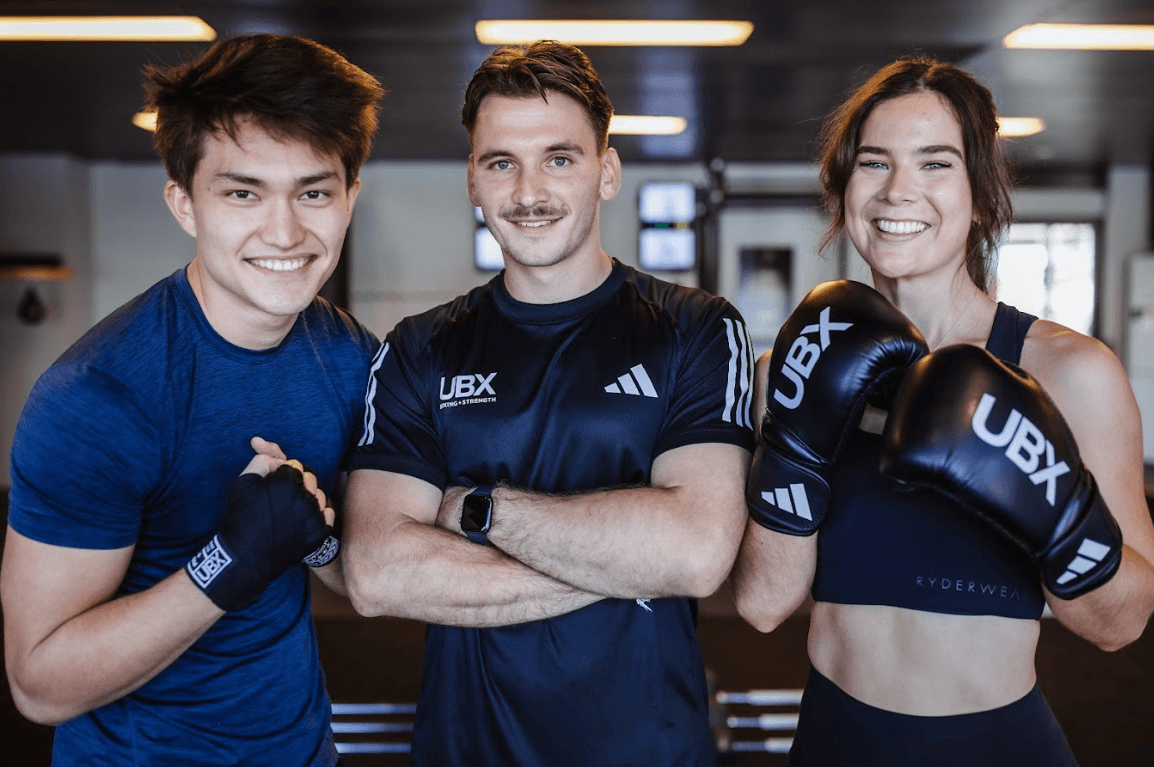 Two male members and one female member posing together and smiling after a session at UBX Training Ealing.