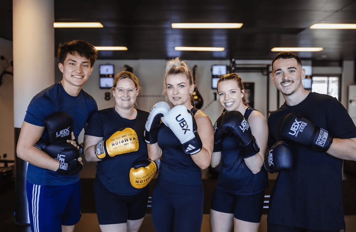 A group of UBX Training Ealing members posing together and smiling after a high-energy workout session.