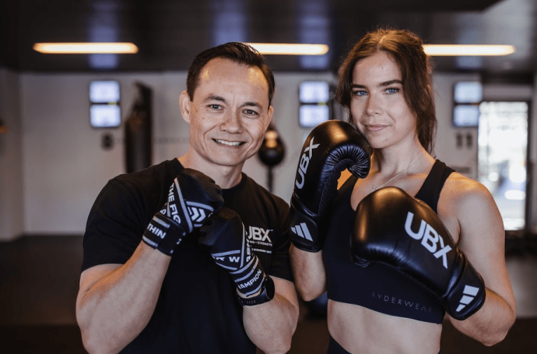 Male and female members smiling and posing for the camera after a workout at UBX Training Ealing.